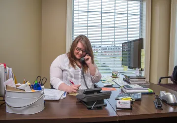 A student working at a desk answering a phone