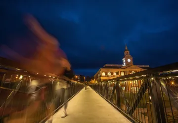 A student walks across the viaduct at night. 