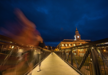 A student walks across the viaduct at night. 