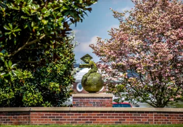 Bronze statue of a boy studying while seated on a globe