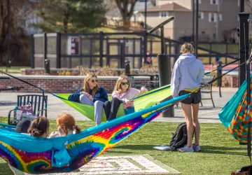 Students sitting on hammocks in a courtyard