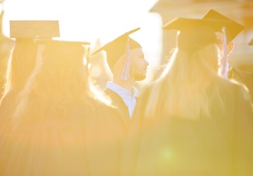 Students wearing cap and gown at sunset