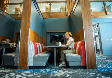 A student sitting in a booth and using a laptop