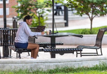 A student sits outside in the quad doing coursework 