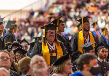 Students stand during commencement and are recognized for their academic accomplishments. 