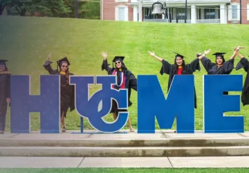 Students celebrate at the Cumberlands HOME sign during graduation. 