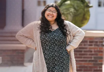 A student poses after class in front of the education building. 