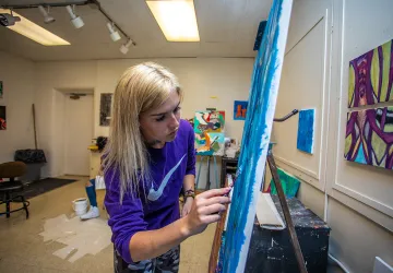 An art student works on a painting in the studio. 