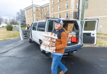 A student carries donated food into a food pantry. 
