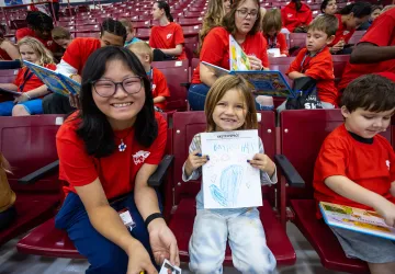 An international student helps an elementary student with a coloring. 