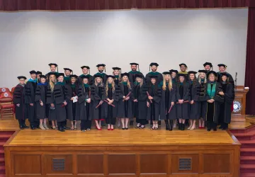 The first graduating class from the DPT program post on stage for a photo. 