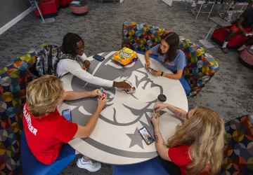 Students play cards around a table in the student center.