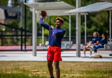 A student throws a football in Patriot Park.