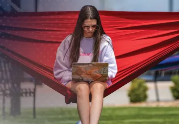 A student works on a computer from her hammock.