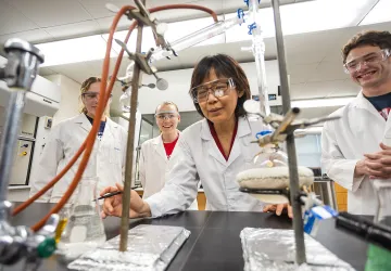 A chemistry professor shows an experiment to students in a lab.