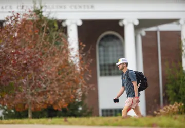 A student walks to class with his backpack. 