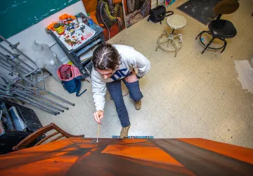 A male art student works on an abstract canvas. 