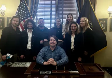 Students from the Upsilon Upsilon honor society at Cumberlands pose behind a desk. 