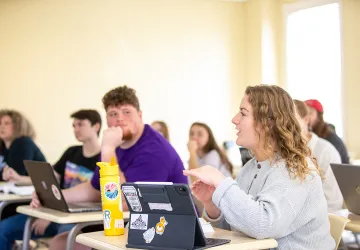A female student discusses a topic in class. 