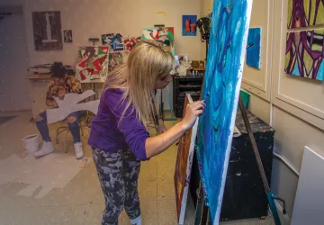 A female art student paints on her canvas. 