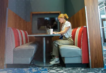 A female college student studies alone at a booth in the library.