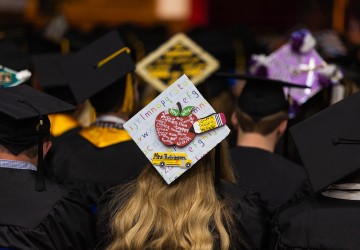 A decorated graduation hat with a teacher motif. 