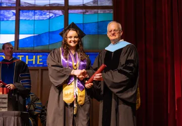 A female honors student accepts her diploma from President Cockrum. 