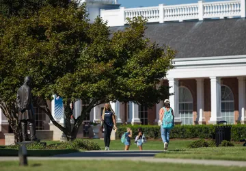 Two students walk on campus near the Lincoln statue. 