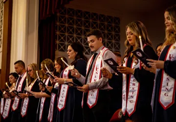 Nursing graduates hold candle and read their oath during a ceremony. 