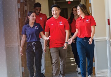 Six physical therapy students walk down a hallway after class. 