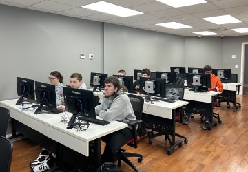 Students work on a computer exercise during a Day of Cyber event. 