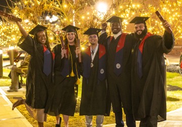 Five students pose in their caps and gowns while holding their diplomas following Cumberlands December graduation ceremony. 