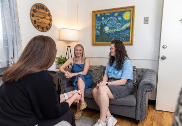 Two female college students visit with an advisor in the campus counseling center. 