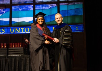 A female graduate accepts her diploma from President Young. 