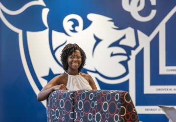 A female student sits in a chair in front of a wall with the Cumberlands logo in the student success center. 