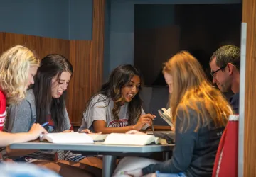 A group of students study together at a table in the library. 