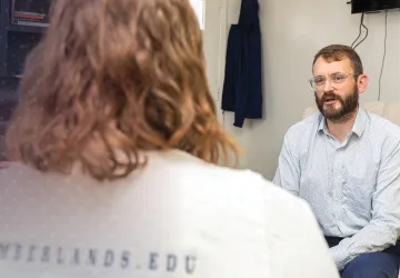A student speaks to a counseling expert inside the counselor's office. 
