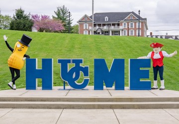 The Mr. Peanut mascot and Cumberlands mascot Patriot Pete stand by the home sign on campus. 