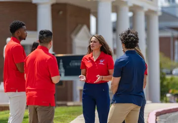 A female physical therapy student leads a discussion among a group of students. 