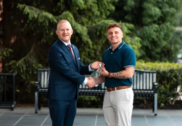 President Young presents an academic award to graduate Jacob Canada.