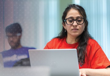 A female students engages in research while on her computer in class. 
