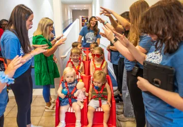 Workers at the Mighty Oaks Early Learning Center push children in a stroller. 