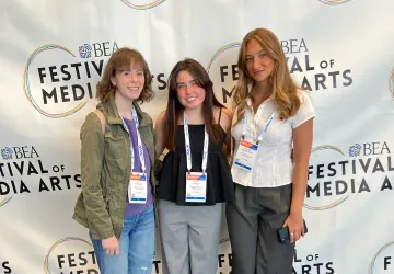 Three college newspaper staff members pose after winning an award. 
