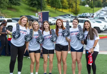 Six female students hold up Pats foam fingers during a welcome week event. 
