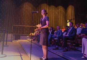 A female law student stands at a microphone and asks a question of Supreme Court members during a campus event. 