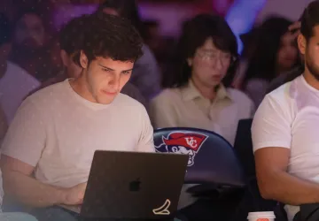 A group of students shown sitting in a seminar with their laptops out. 