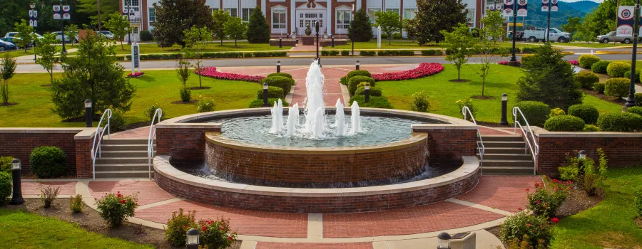 A water fountain in the middle of the college campus. 