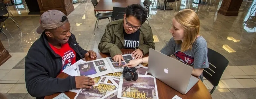 Three people sitting while looking at Newspapers