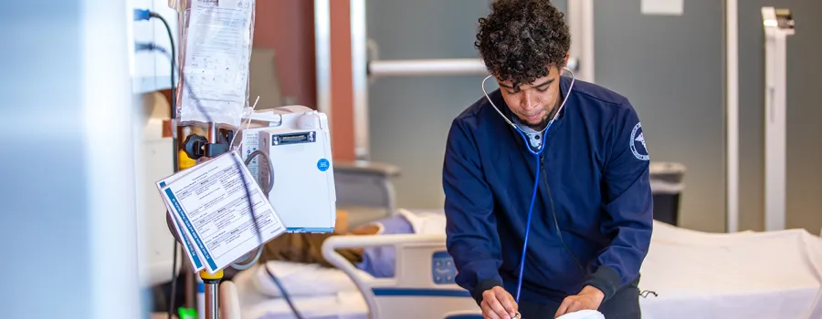 A nursing student works through an exam on a simulated patient. 
