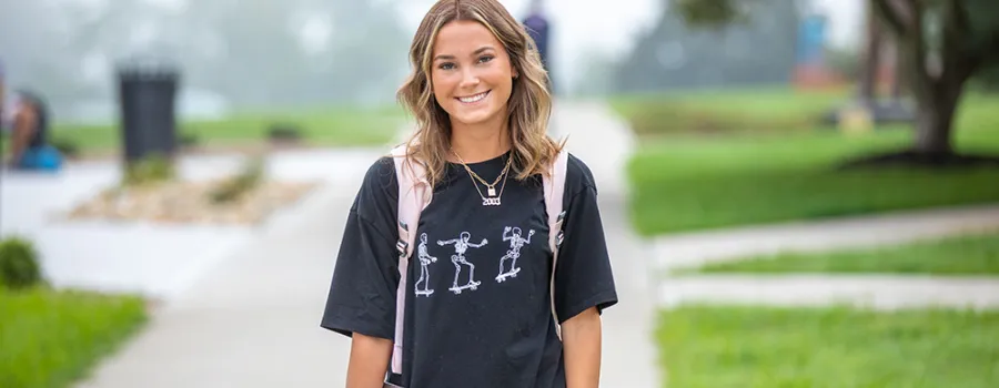 Young woman wearing backpack standing outdoors.